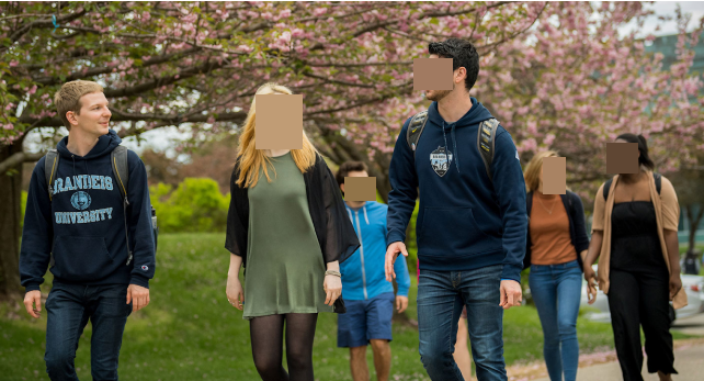 Students walking on a college campus with one person's face visible and all others pixelated